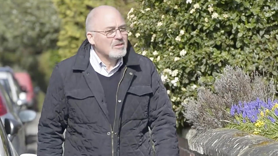 Retired pharmacist Stuart Newsome, 64, walking in his street in Ripon, North Yorkshire, to see if any of his neighbours have displayed either a green or red card in their front window depending on whether they required assistance.