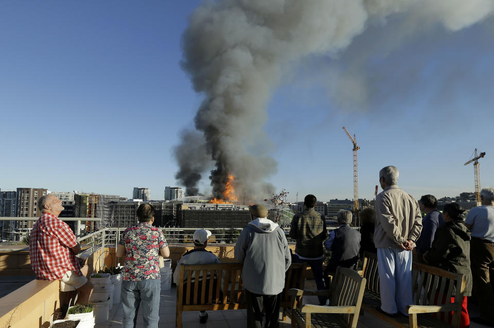 Residents at Mission Creek Senior Community building look from their roof at a fire burning in San Francisco, Tuesday, March 11, 2014. (AP Photo/Jeff Chiu)