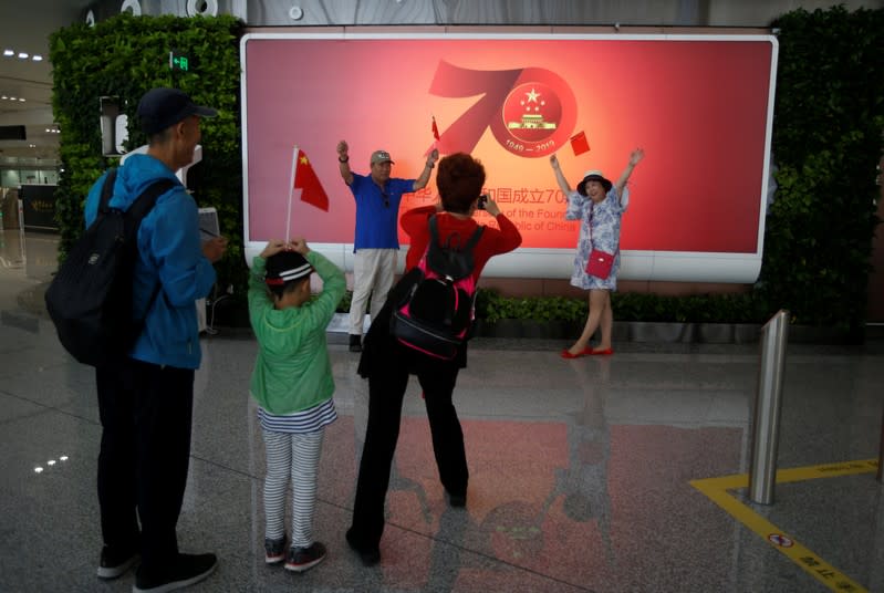 People pose for a photo in front of a poster at the terminal hall of the newly launched Daxing International Airport on the outskirts Beijing