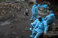 Health workers wearing personal protective equipment wait near the body of a person who died of COVID 19 at a cremation ground in Gauhati, India, Thursday, Sept. 10, 2020. India is now second in the world with the number of reported coronavirus infections with over 5.1 million cases, behind only the United States. Its death toll of only 83,000 in a country of 1.3 billion people, however, is raising questions about the way it counts fatalities from COVID-19. (AP Photo/Anupam Nath)