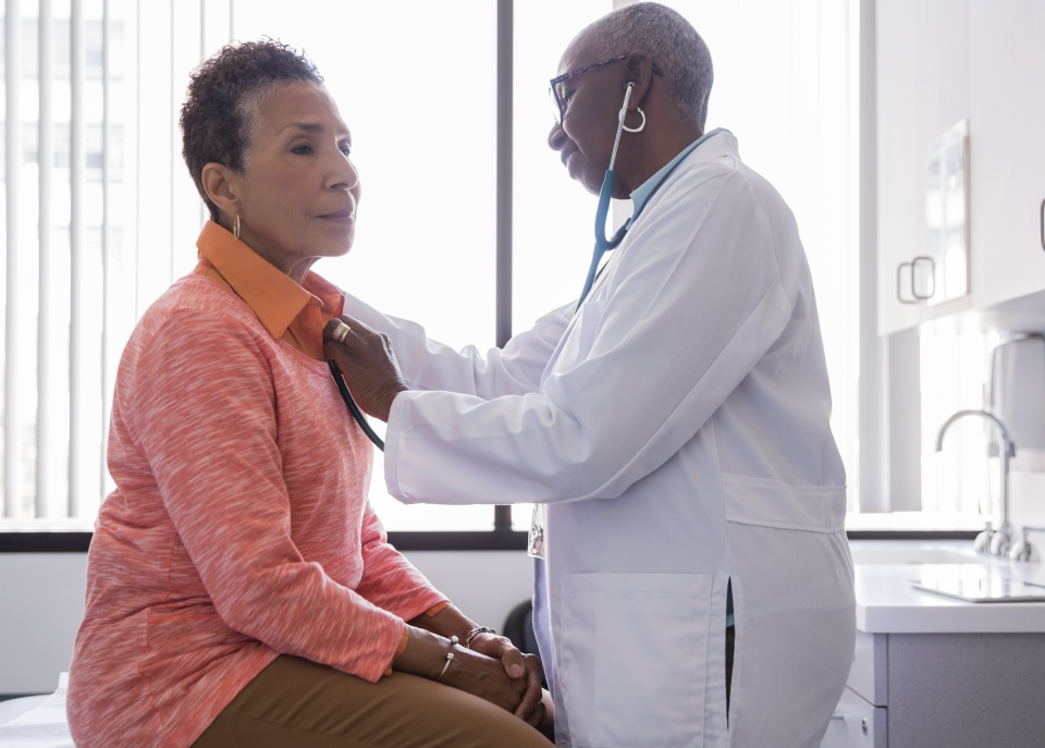 Doctor listening to patient's heart with stethoscope during medical exam