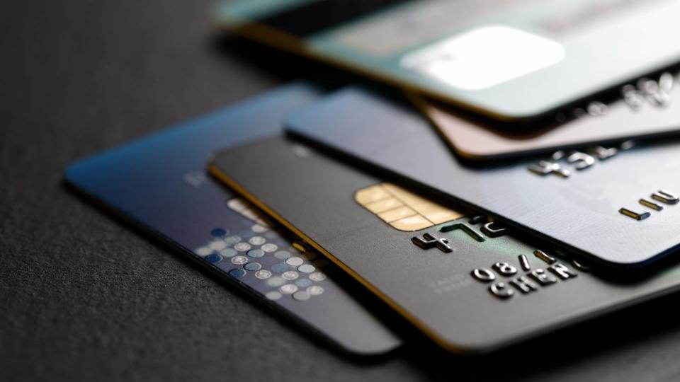 stack of multicolored credit cards on black background.