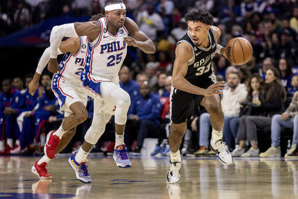 San Antonio Spurs guard Tre Jones (33) is followed down court by Philadelphia 76ers forward Danuel House Jr. (25) in the first half of an NBA basketball game, Saturday, Oct. 22, 2022, in Philadelphia. (AP Photo/Laurence Kesterson)