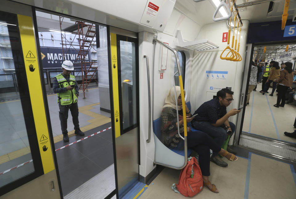 In this Feb. 21, 2019, photo, people ride on a Mass Rapid Transit (MRT) during a trial run in Jakarta, Indonesia. Commuting in the gridlocked Indonesian capital will for some involve less frustration, sweat and fumes when its first subway line opens later this month. The 10-mile system running south from Jakarta's downtown is the first phase of a development that if fully realized will plant a cross-shaped network of stations in the teeming city of 30 million people. (AP Photo/Achmad Ibrahim)