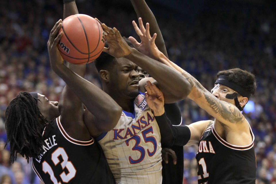 Kansas center Udoka Azubuike (35) rebounds between Oklahoma State guards Isaac Likekele (13) and Lindy Waters III (21) during the first half of an NCAA college basketball game in Lawrence, Kan., Monday, Feb. 24, 2020. (AP Photo/Orlin Wagner)