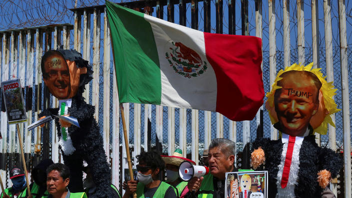 Migrants hold up pinatas with pictures of Mexican Foreign Minister Marcelo Ebrard and former U.S. President Donald Trump during a protest at the border fence in Playas Tijuana to demand the U.S. government to lift a public health order known as Title 42, a COVID-era policy that allows the expulsion of migrants to prevent the spread of the virus, in Tijuana, Mexico April 29, 2022. <span class="copyright">REUTERS/Jorge Duenes</span>