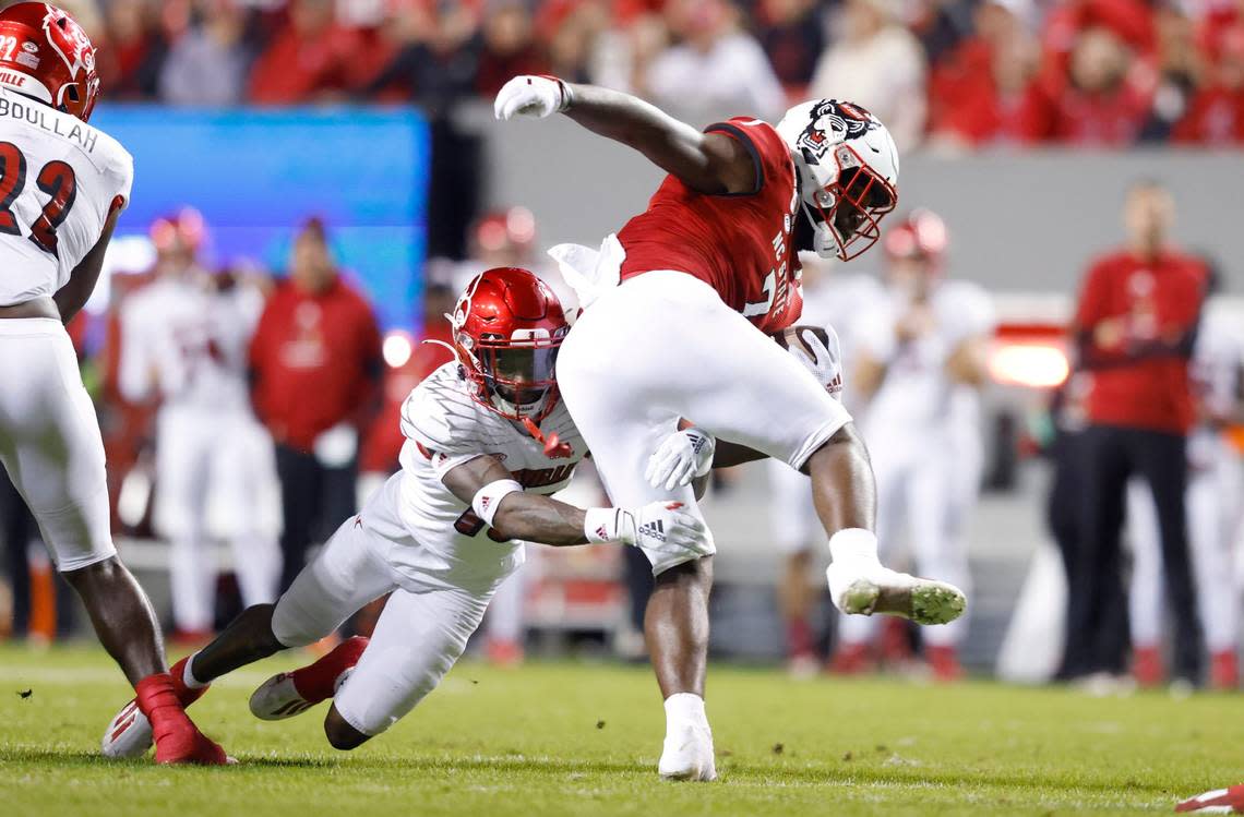 N.C. State running back Zonovan ‘Bam’ Knight (7) tries to break free from Louisville defensive back Kei’Trel Clark (13) during the first half of N.C. States game against Louisville at Carter-Finley Stadium in Raleigh, N.C., Saturday, October 30, 2021. Ethan Hyman/ehyman@newsobserver.com