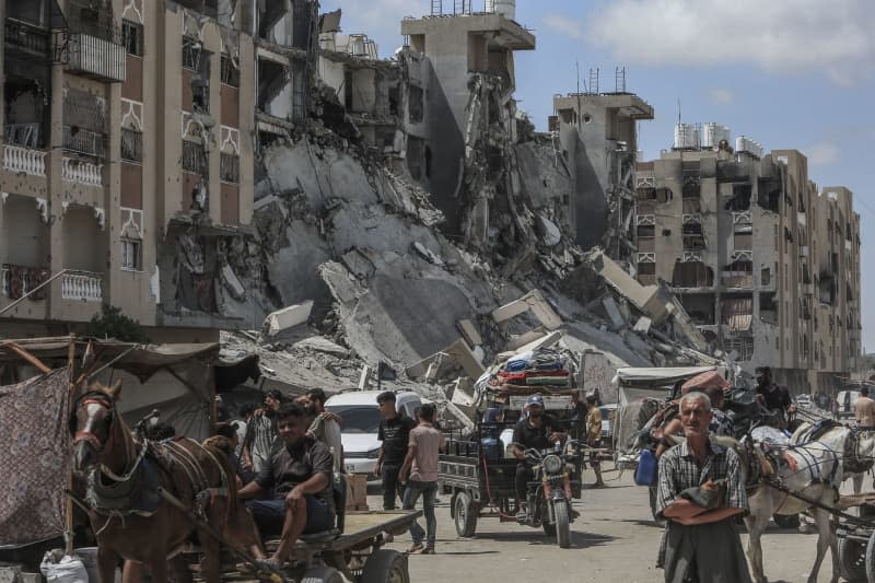 Palestinians carry their belongings as they flee Hamad City towards Al-Mawasi after the Israeli army dropped leaflets demanding that residents of a northern neighborhood in Khan Younis evacuate immediately ahead of a new military operation in the Gaza Strip. Abed Rahim Khatib/dpa