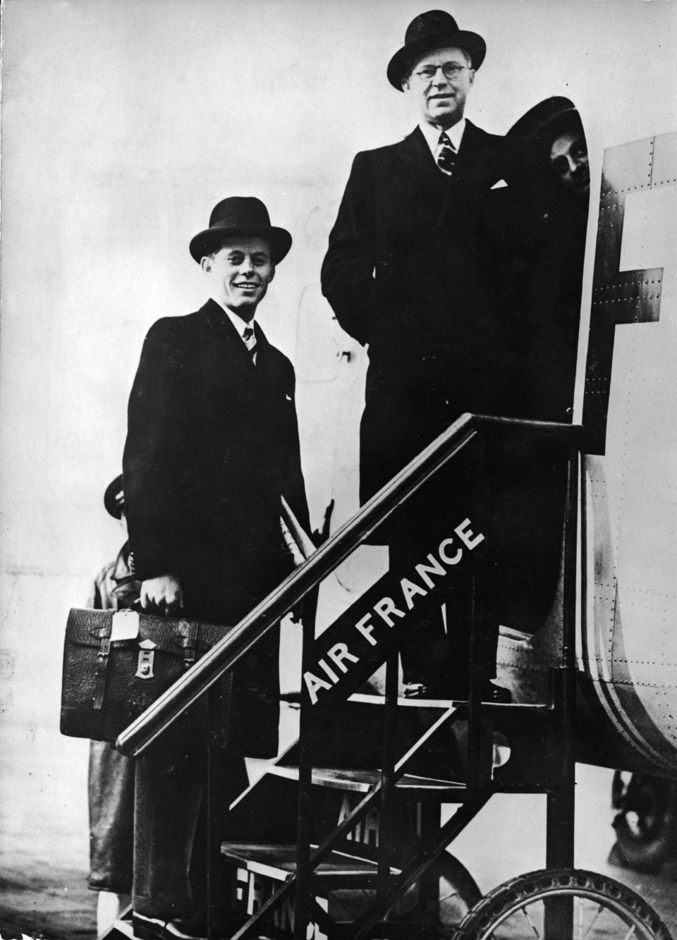 Joe Kennedy Sr. and John F. Kennedy pose for a photograph while boarding a plane in 1939.