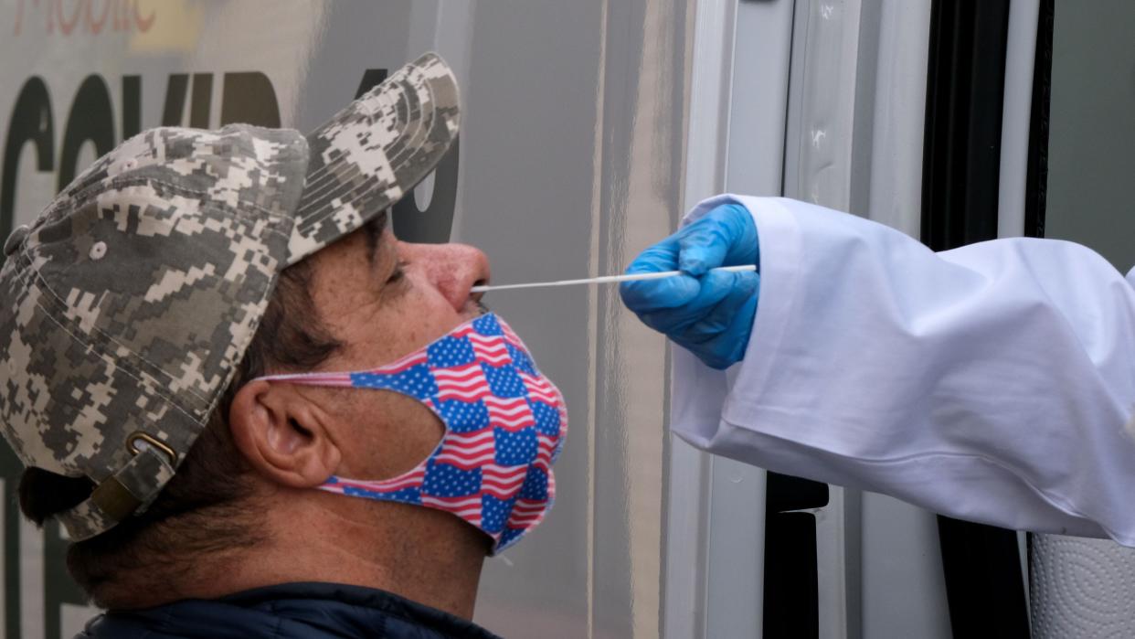 A man wearing a mask is tested for COVID.