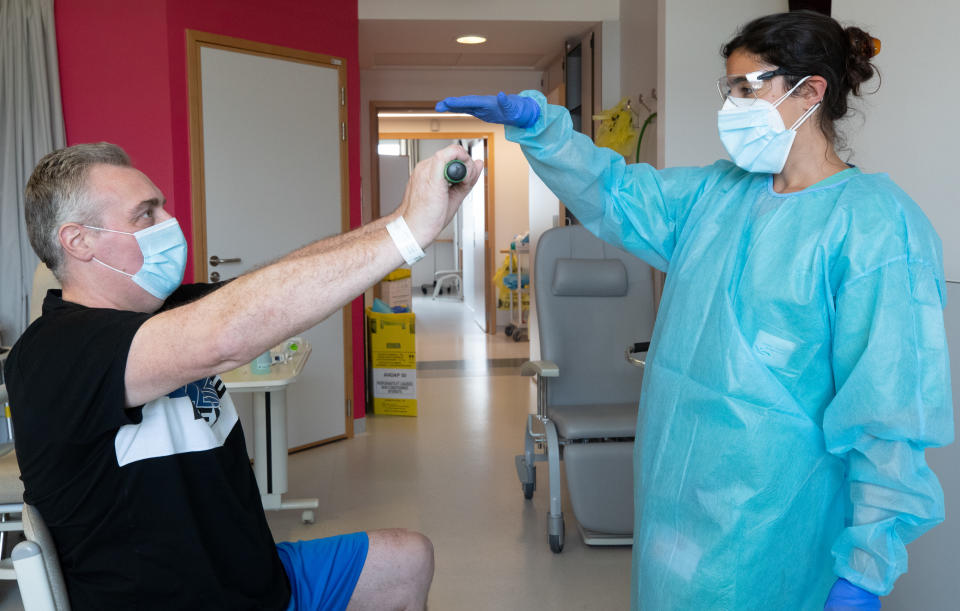 Belgian physiotherapist Mounya El Khalil (R) and her patient Michel Renard attend a therapy session in the revalidation centre for COVID-19 patients discharged from the hospital, on April 28, 2020, in Tournai. - This patient will go out on April 30 after two weeks of coma with a respirator and one week of physiotherapy. Belgium is in its seventh week of confinement in the ongoing corona virus crisis. The government has announced a phased plan to attempt an exit from the lockdown situation in the country, continuing to avoid the spread of Covid-19. (Photo by BENOIT DOPPAGNE / BELGA / AFP) / Belgium OUT (Photo by BENOIT DOPPAGNE/BELGA/AFP via Getty Images)