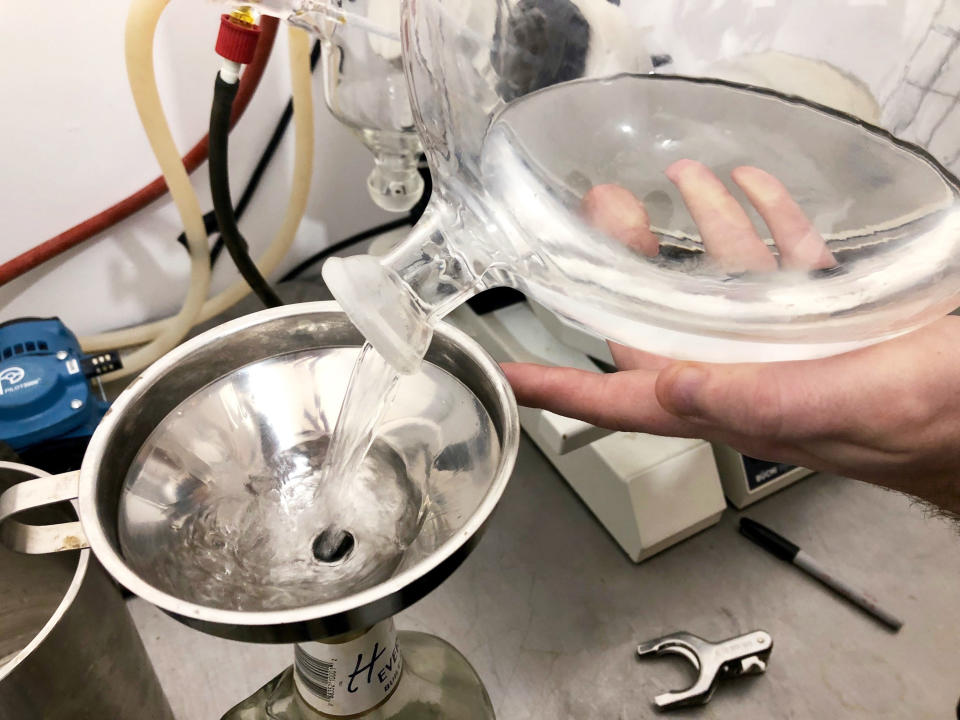 ADVANCE FOR PUBLICATION ON TUESDAY, JUNE 11, AND THEREAFTER - In this April 10, 2019, photo, the hands of Fletcher Gerhardt, a contractor at a medical marijuana processing company called PharmaEx LLC, are seen through a glass beaker as Gerhardt works to process hash oil in Rickreall, Ore. PharmaEx LLC is the last medical marijuana processing company in Oregon. An Associated Press analysis has found existing medical marijuana programs take a hit when states legalize cannabis for all adults. (AP Photo/Gillian Flaccus)