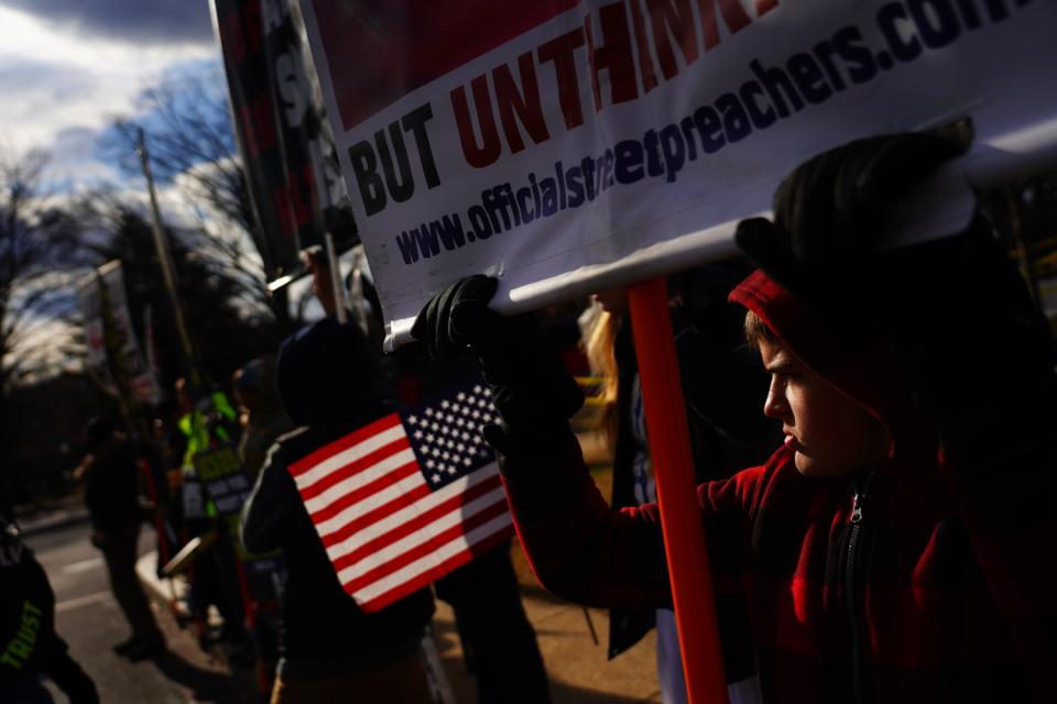 Protesters stand near the the perimeter of the Capitol grounds before the start of the 59th presidential inauguration.