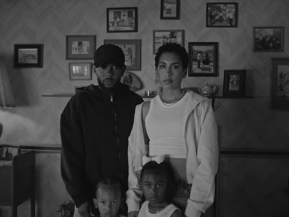 A screengrab of "Not Like Us" music video featuring a black and white image of Kendrick Lamar, Whitney Alford and their two children.