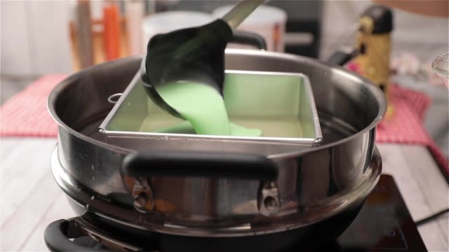 Pouring green kueh lapis batter into baking tin