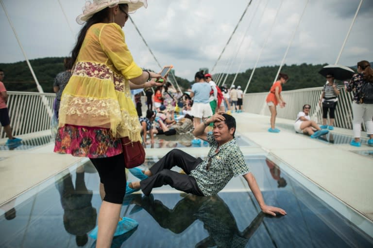 A tourist takes a photograph on the world's highest and longest glass-bottomed bridge above a valley in Zhangjiajie in China's Hunan province