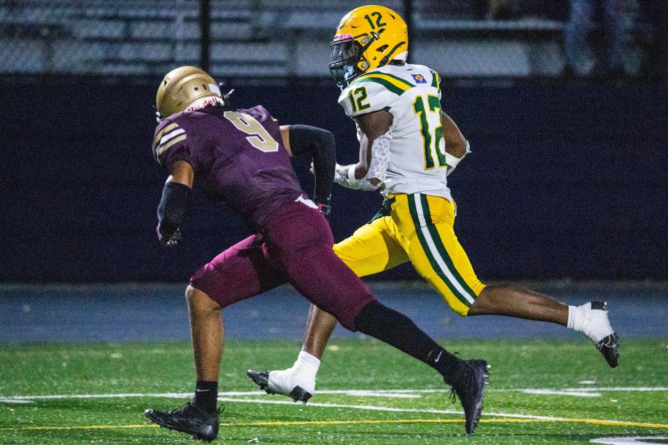 Indian River junior Jayvion Chandler (12) runs the ball side-by-side with St. Elizabeth junior Jose Maldonado (9) during the football game at Abessinio Stadium in Wilmington, Friday, Sept. 15, 2023. Indian River won 20-14.