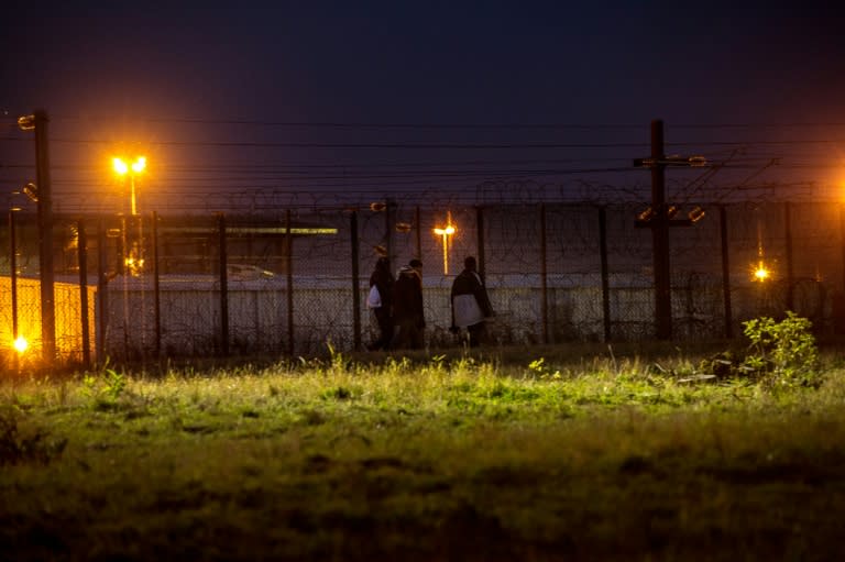 Migrants inside the Eurotunnel site try to find a way to cross the fences topped with barbed wire that protect the boarding platform, in Coquelles near Calais, northern France, on July 31, 2015