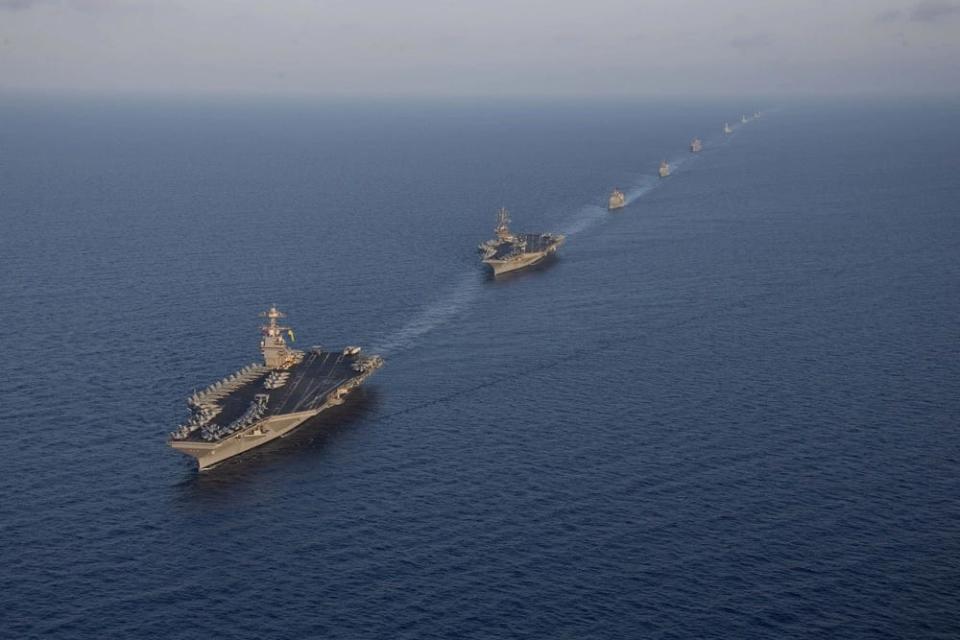 a line of military ships sail in formation