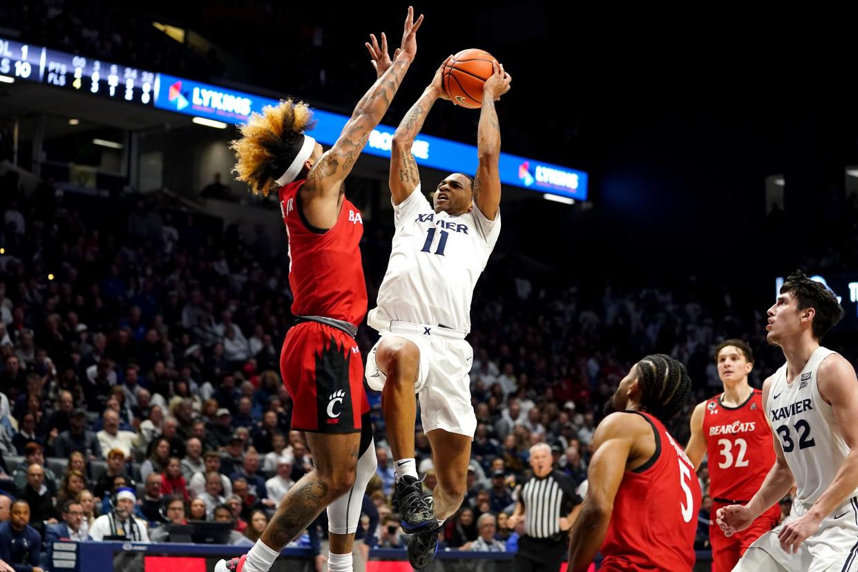 Xavier Musketeers guard Dwon Odom (11) rises to the basket as Cincinnati Bearcats guard Mike Saunders (3) defends in the second half of the 89th Annual Crosstown Shootout college basketball game, Saturday, Dec. 11, 2021, at Cintas Center in Cincinnati. The Xavier Musketeers won, 83-63.