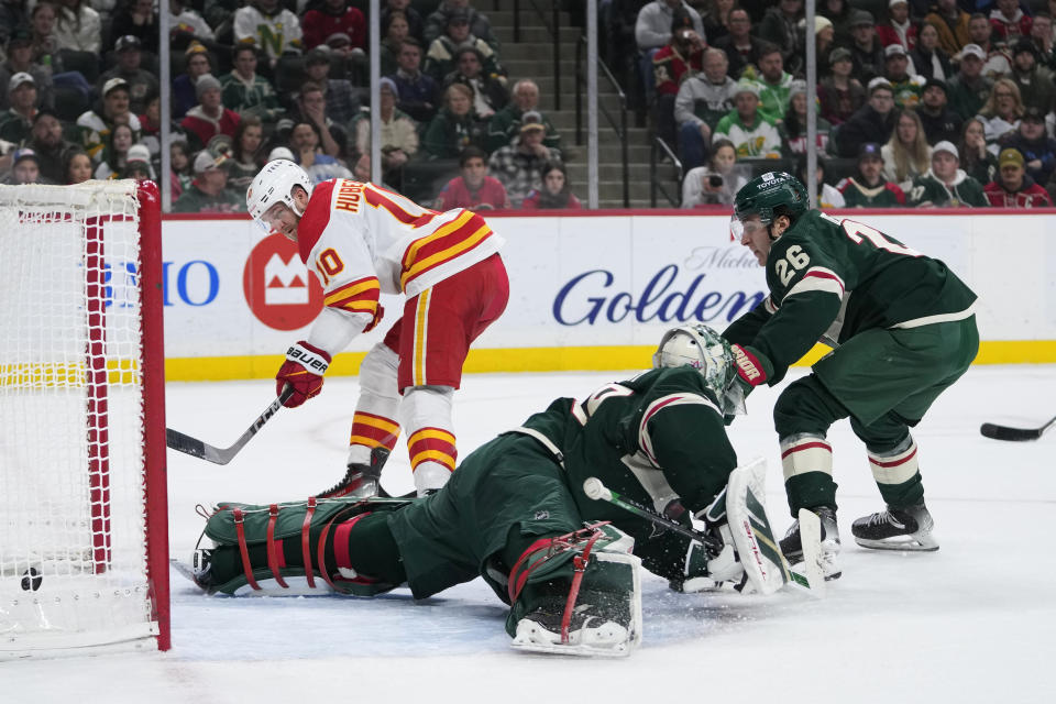 Calgary Flames center Jonathan Huberdeau (10) scores a goal past Minnesota Wild goaltender Marc-Andre Fleury, center, and center Connor Dewar (26) during the first period of an NHL hockey game Tuesday, Jan. 2, 2024, in St. Paul, Minn. (AP Photo/Abbie Parr)