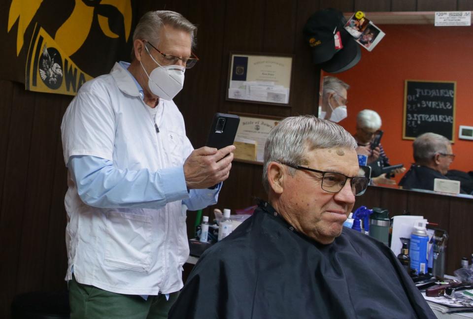 Tom Bergman snaps a photo of customer Bruce Temple's haircut so he will have reference photo to show his new barber Wednesday, Dec. 13, 2023 in Iowa City, Iowa.