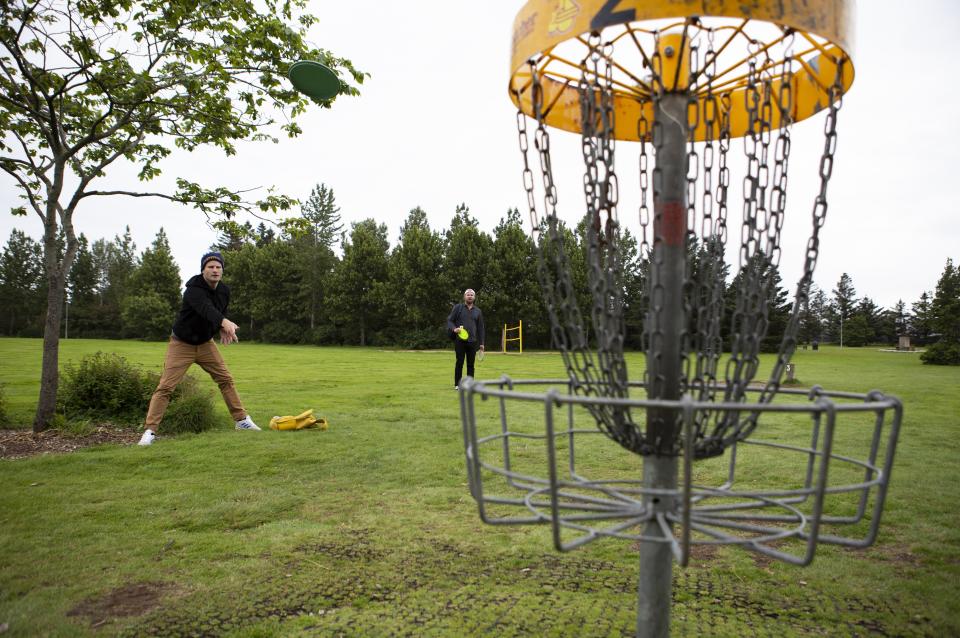 Sveinn Skorri Höskuldsson, left, and Jón Vigfús play frisbee golf at Klambratrún in downtown Reykjavik, Iceland Saturday Aug. 1, 2020. In Iceland, a nation so safe that its president runs errands on a bicycle, U.S. Ambassador Jeffery Ross Gunter has left locals aghast with his request to hire armed bodyguards. He's also enraged lawmakers by casually and groundlessly hitching Iceland to President Donald Trump's controversial "China virus” label for the coronavirus. (AP Photo/Árni Torfason)