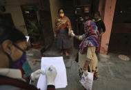 A health worker reads the temperature of a woman during a door to door survey to assess the COVID-19 situation in New Delhi, India, Monday, Nov. 23, 2020. India has more than 9 million cases of coronavirus, second behind the United States. (AP Photo/Manish Swarup)