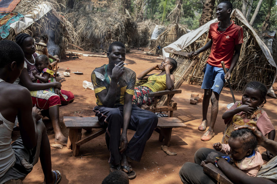 Saint-Cyr Boussa smokes a cigarette, surrounded by his brothers in the village of Cesacoba, Central African Republic, Sunday Feb. 14, 2021. "We ran away from our village to save our lives," said Boussa. An estimated 240,000 people have been displaced in the country since mid-December, according to U.N. relief workers, when rebels calling themselves the Coalition of Patriots for Change launched attacks, causing a humanitarian crisis in the already unstable nation. (AP Photo/Adrienne Surprenant)