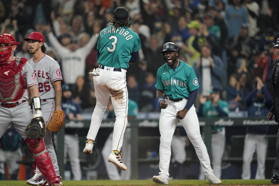 Seattle Mariners' J.P. Crawford (3) celebrates with Taylor Trammell, right, after they both scored on a three-run double hit by Ty France during the fourth inning of a baseball game against the Los Angeles Angels, Friday, June 17, 2022, in Seattle. (AP Photo/Ted S. Warren)
