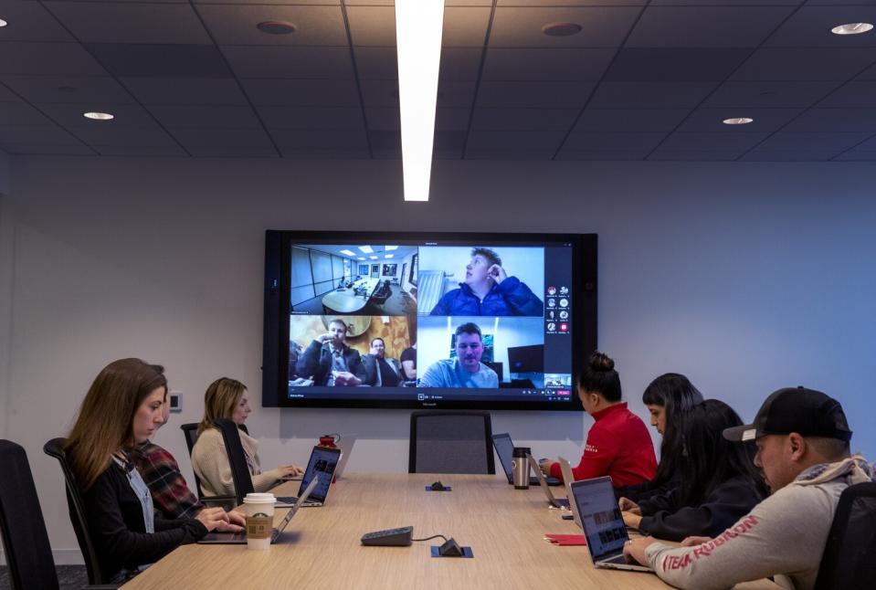 People using laptops at a table during a video conference