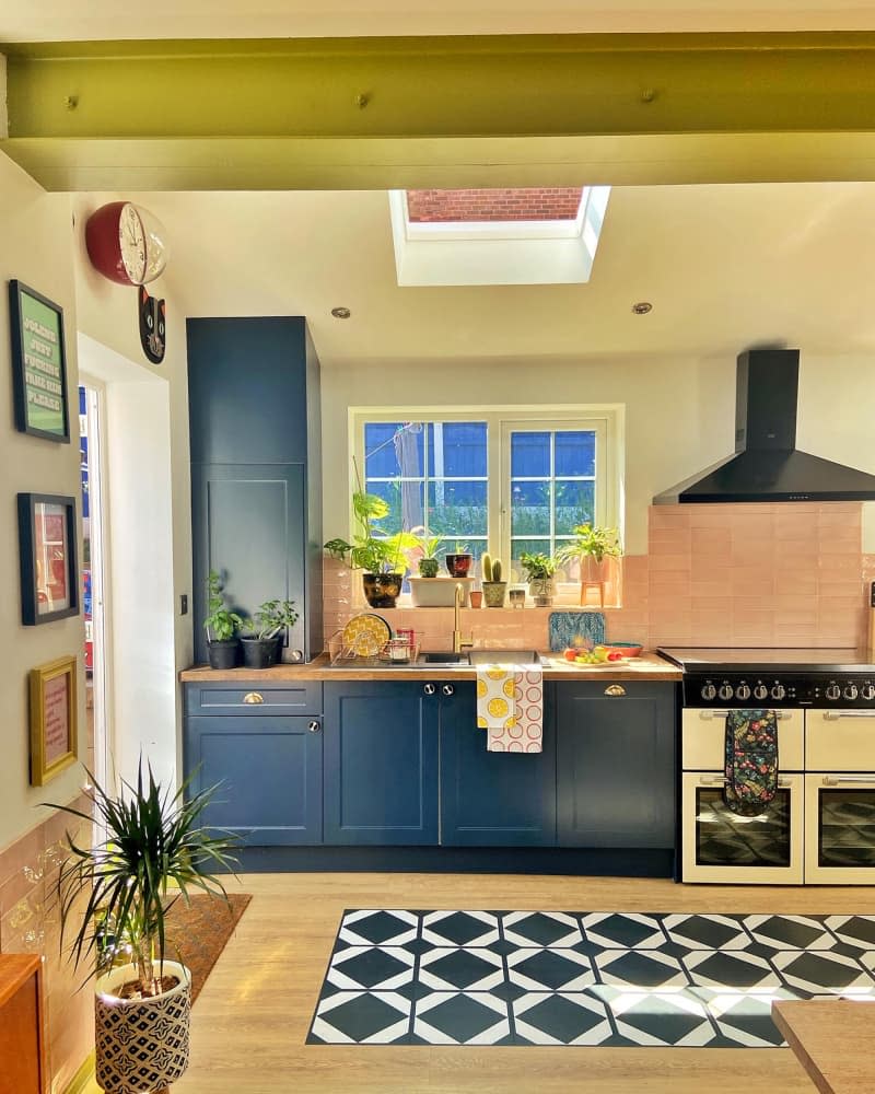 Pink backsplash in kitchen with blue cabinets.