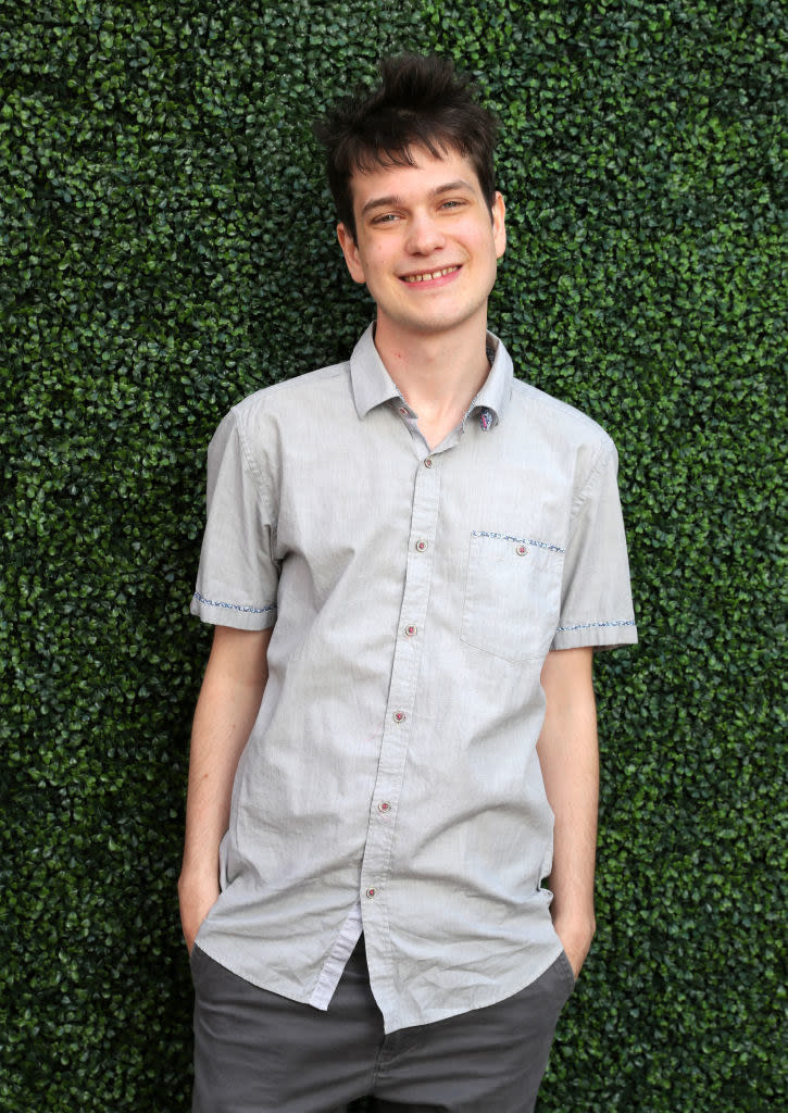 Liam smiling in front of a verdant background