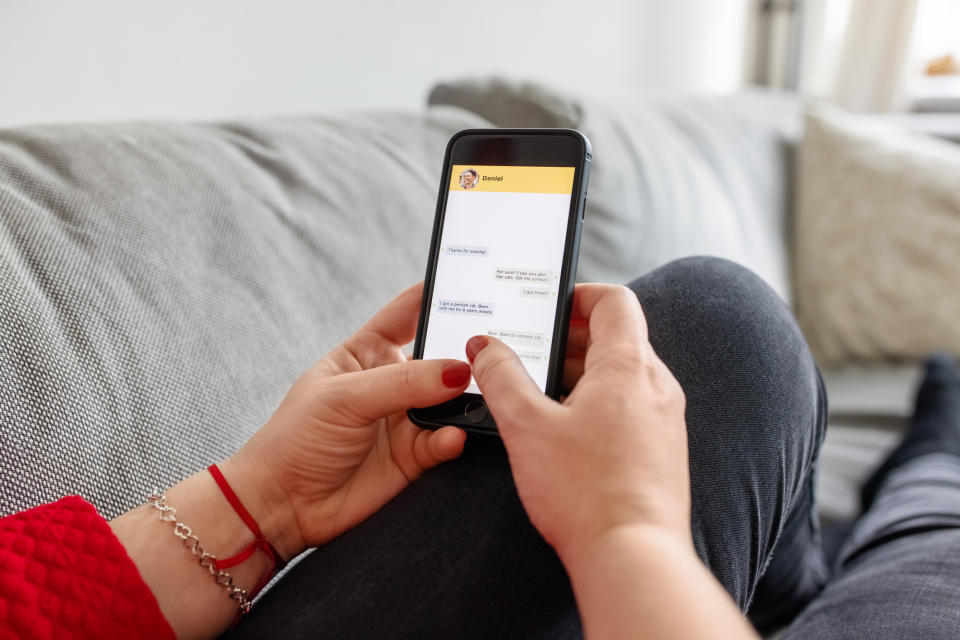 Person browsing on phone with visible app interface, seated indoors