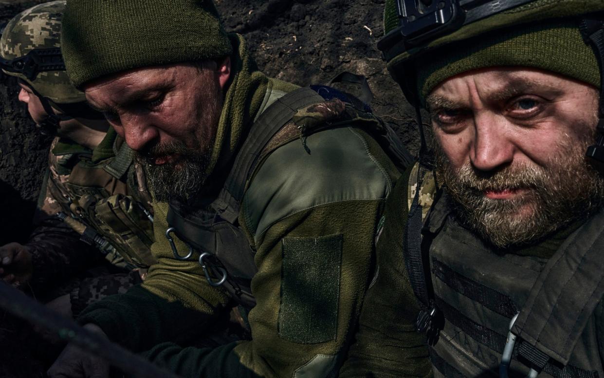 Ukrainian soldiers sit in a trench along the frontline during fighting with Russian troops near Bakhmut - Libkos/AP