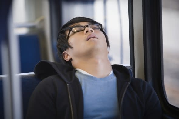 Close-up of a young man sleeping on a commuter train