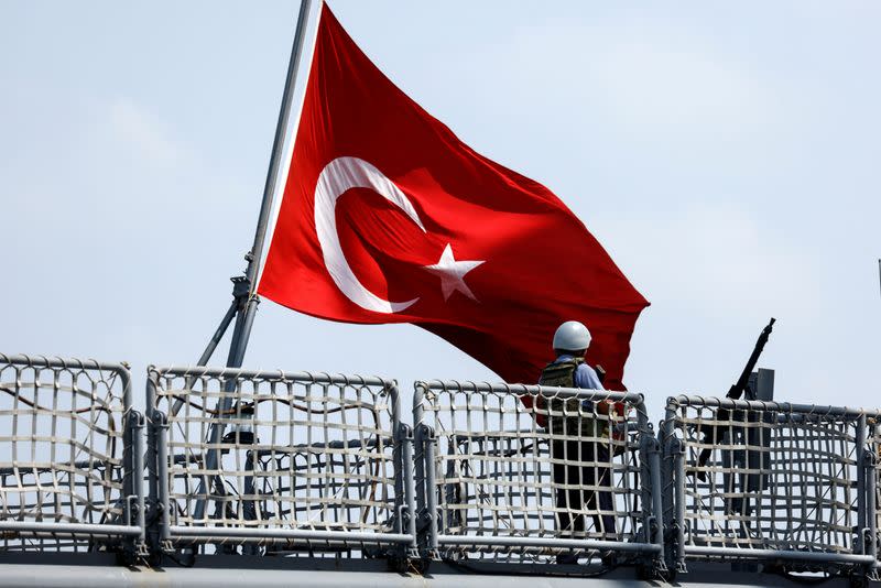 A military personnel stands by a Turkish national flag on a naval frigate as it is berthed at Haifa Port