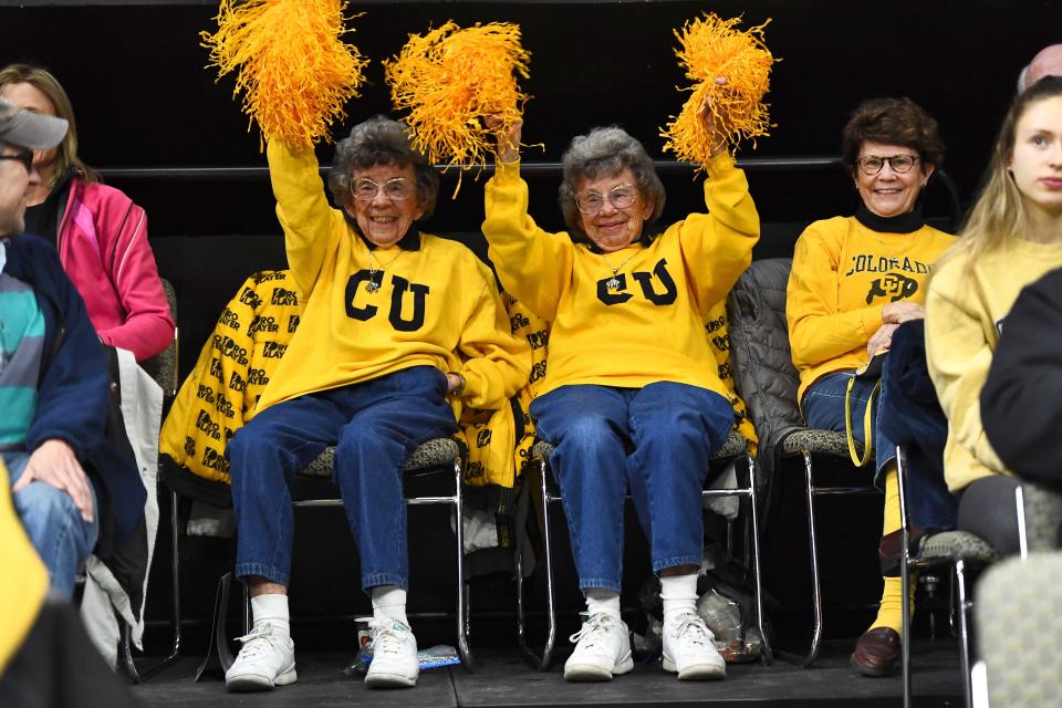 Die Colorado-Fans Peggy Coppom (links) und ihre Zwillingsschwester Betty Hoover feuerten die Basketballmannschaft der Männer während eines Spiels 2019 in Boulder an.  Betty starb im Jahr 2020.
