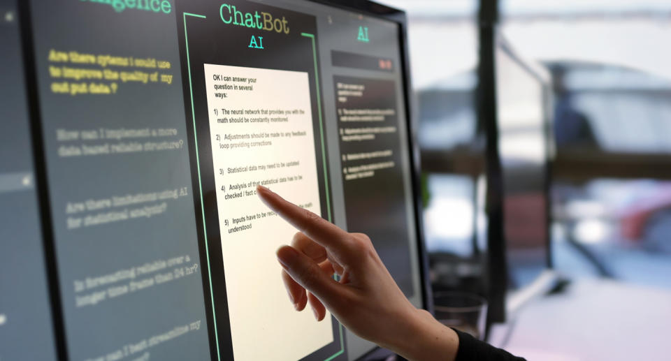 A hand reaches out to a screen saying ChatBot AI.