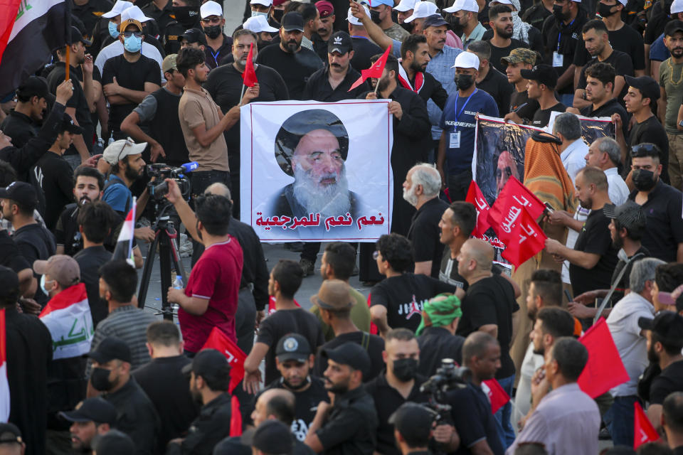 FILE - Supporters of Iran-backed Shiite Coordination Framework attend a rally to denounce their rivals, followers of an influential Shiite cleric Muqtada al-Sadr who stormed the parliament last month and have since been holding a sit-in outside the assembly building in Baghdad, Iraq, Friday, Aug. 12, 2022. On the photo is a revered Shiite Grand Ayatollah Ali al-Sistani. (AP Photo/Anmar Khalil, File)