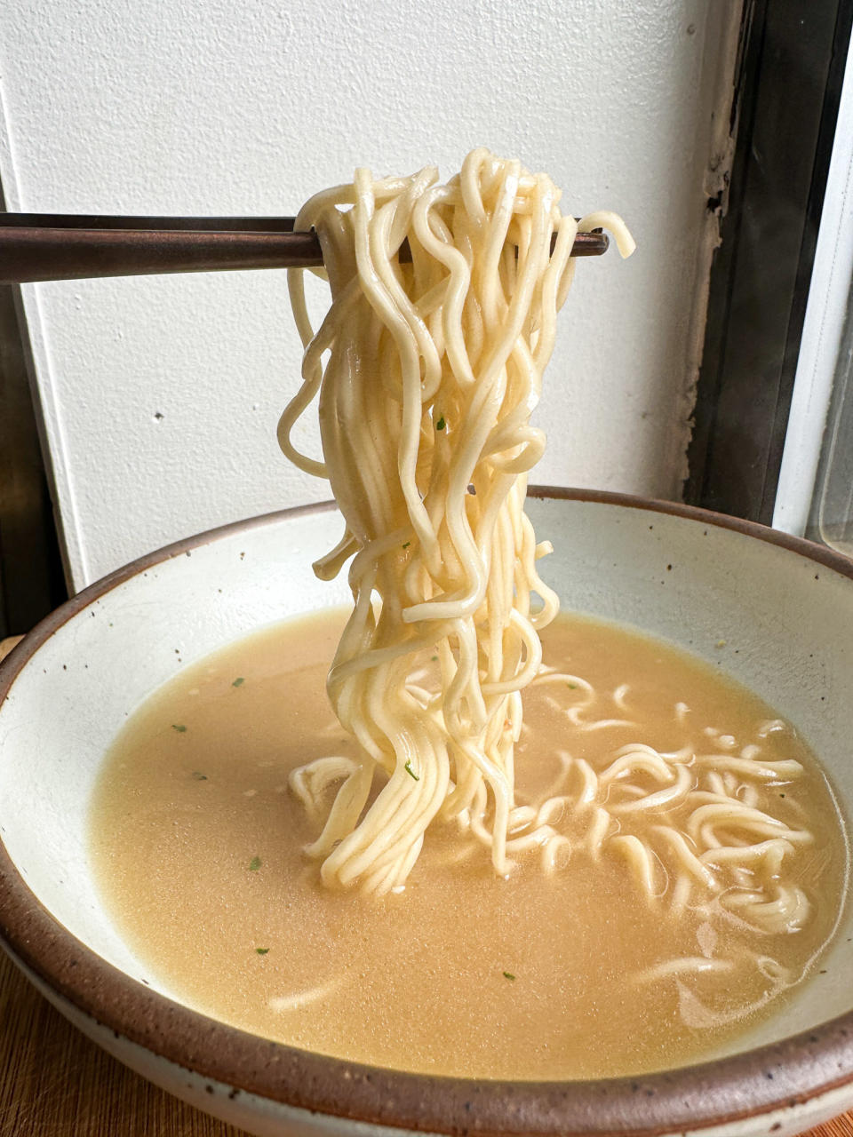 holding up trader joe's noodles in ramen bowl