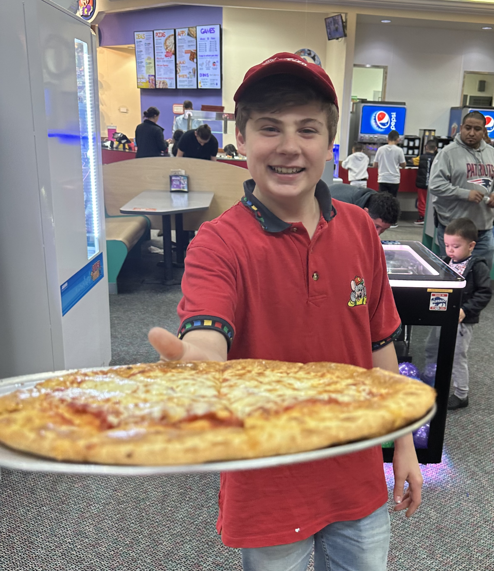 Logan Carreiro, 14, of Swansea, holds a cheese pizza at Chuck E. Cheese. Carreiro started a petition to stop CEC Entertainment from discontinuing its animatronic shows, and his work has paid off.