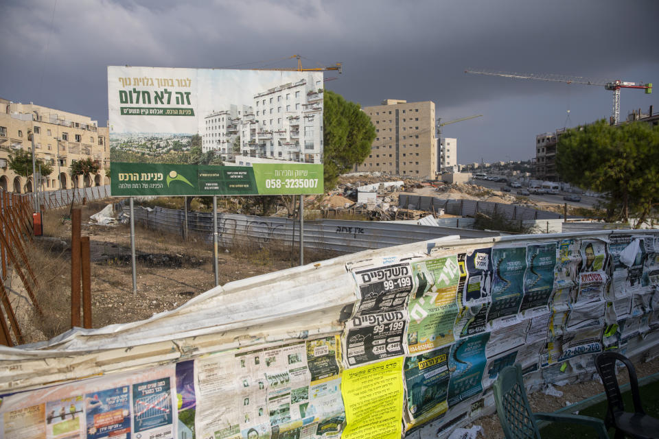 FILE- in this Tuesday, Nov. 10, 2020. A billboard advertises new residential project at a construction site in the east Jerusalem settlement of Ramat Shlomo. International Criminal Court's decision authorizing its chief prosecutor to open a war crimes investigation against Israel could soon be reverberating in the Israeli-occupied West Bank. While any potential probe could look at Israeli military campaigns in the Gaza Strip, Israel's half-century campaign of building settlements on occupied lands appears to be especially vulnerable to prosecution. (AP Photo/Ariel Schalit, FILE)