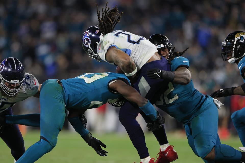 Jacksonville Jaguars linebacker Foyesade Oluokun (23), left, and defensive tackle DaVon Hamilton (52), right, sandwich Tennessee Titans running back Derrick Henry (22) on a combined tackle during the fourth quarter of an NFL football regular season matchup AFC South division title game Saturday, Jan. 7, 2023 at TIAA Bank Field in Jacksonville. The Jacksonville Jaguars held off the Tennessee Titans 20-16. [Corey Perrine/Florida Times-Union]