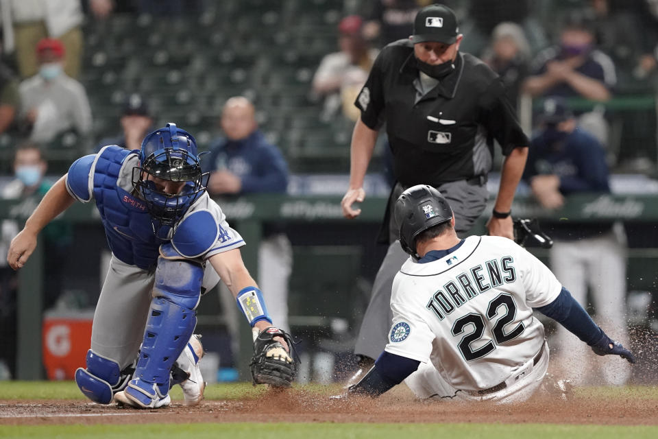 Seattle Mariners' Luis Torrens (22) slides safely home as Los Angeles Dodgers catcher Will Smith attempts the tag during the fourth inning of a baseball game, Monday, April 19, 2021, in Seattle. Torrens scored on a double hit by Taylor Trammell. (AP Photo/Ted S. Warren)