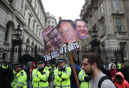 Demonstrators hold placards during a protest outside Downing Street in Whitehall, central London, Britain April 9, 2016. REUTERS/Neil Hall