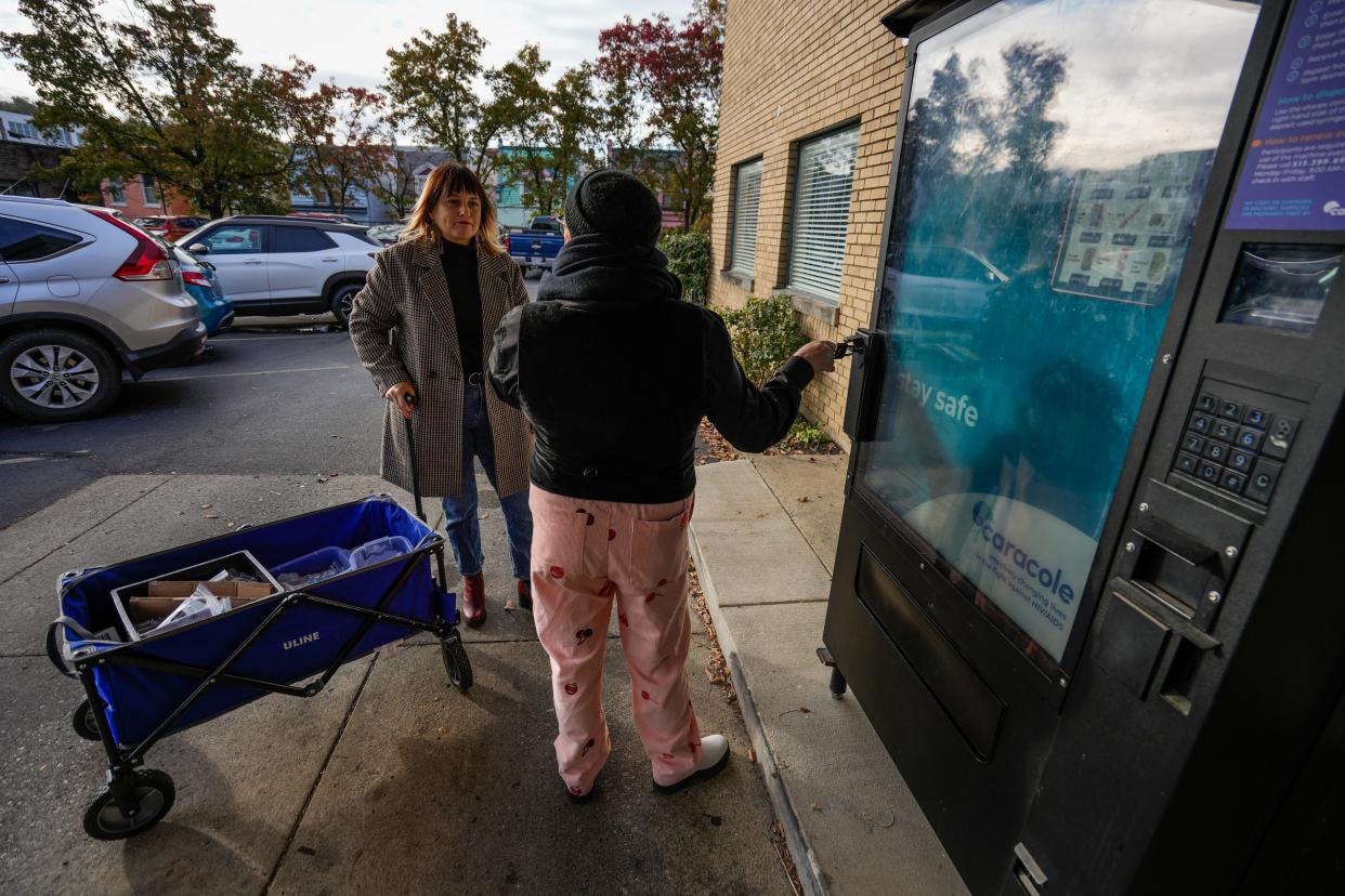 Caracole in Cincinnati has a vending machine with Narcan, clean drug kits, testing kits and other items that can help with harm reduction. Leah Majesky (left) and Krivin Van Sloun refill the vending machine.