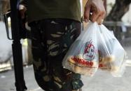 A government soldier carries a plastic bag containing grenade ammunitions for his comrades during a lull in fighting with Muslim rebels from the Moro National Liberation Front (MNLF) in Zamboanga city in southern Philippines September 15, 2013. (REUTERS/Erik De Castro)