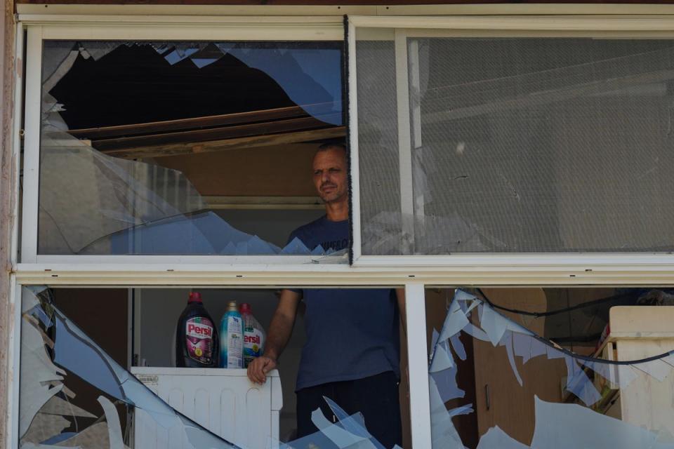 A man looks at a damaged window of a house following an attack in Acre, north Israel (AP)