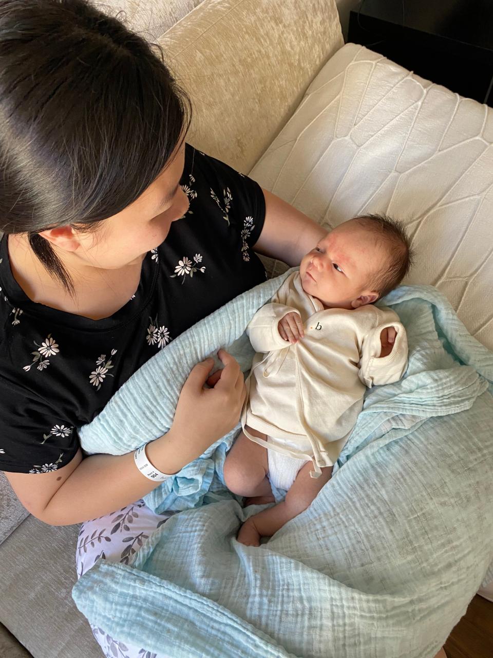 Laura, the mother of four-week-old Felix, looks down at her son adoringly as she prepares to swaddle him with a blanket at Borum Postpartum Retreat.